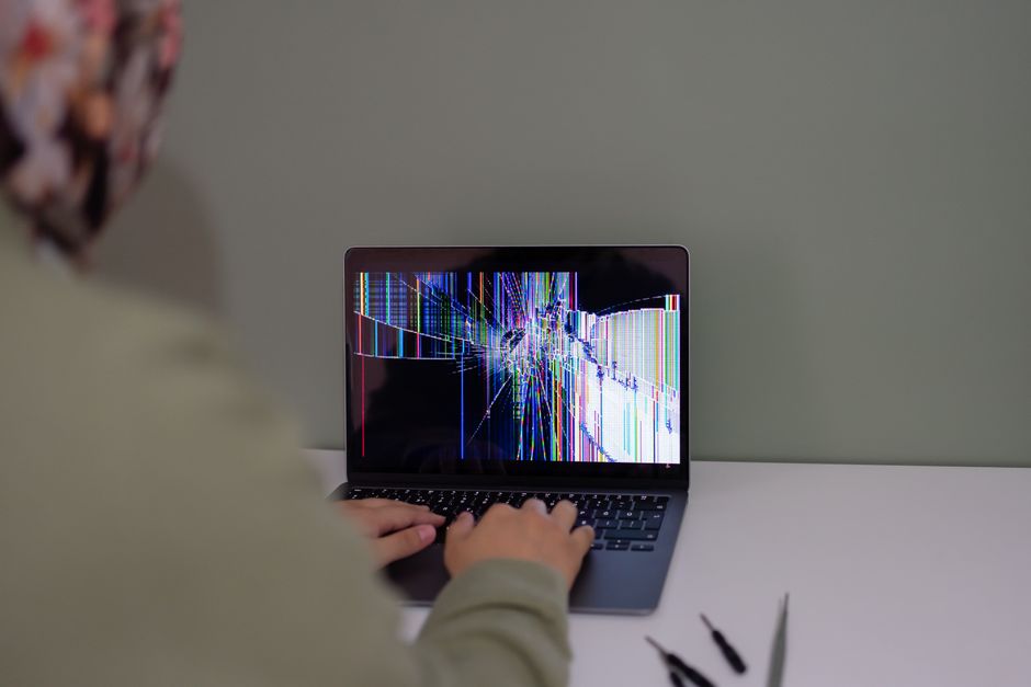 A laptop with a cracked display showing coloured lines