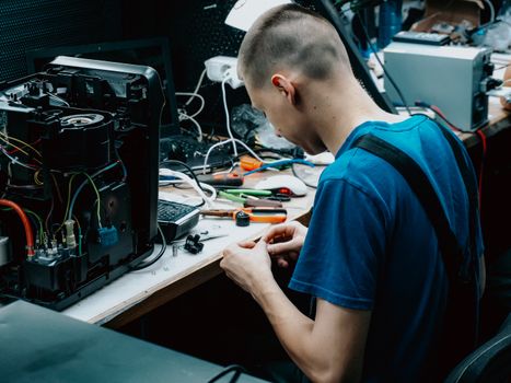 A technician working on electronics at a repair bench