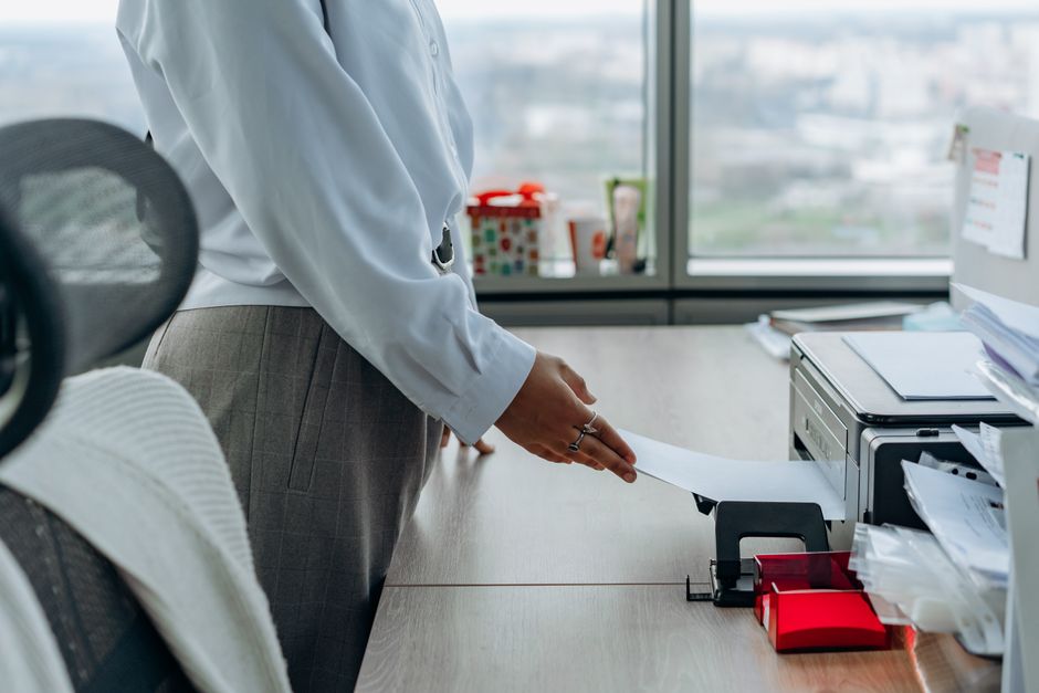 A person collecting a printed page from an office printer